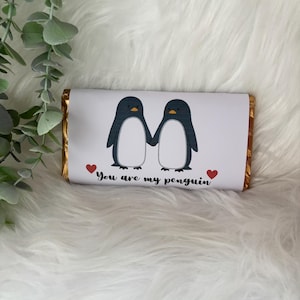 May include: A chocolate bar with a white wrapper featuring two cartoon penguins holding hands. The penguins are black and white with yellow beaks. The text "You are my penguin" is below the penguins, with a red heart on each side.