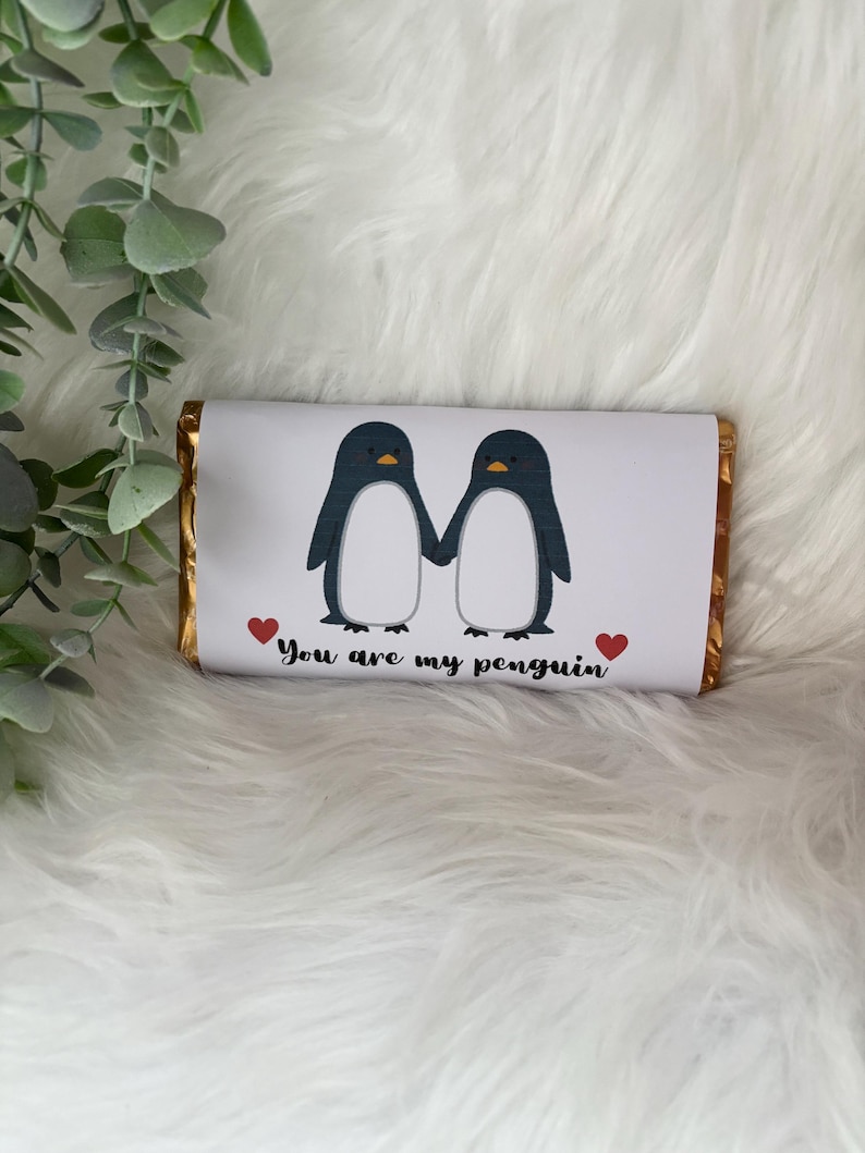 May include: A chocolate bar with a white wrapper featuring two cartoon penguins holding hands. The penguins are black and white with yellow beaks. The text "You are my penguin" is below the penguins, with a red heart on each side.