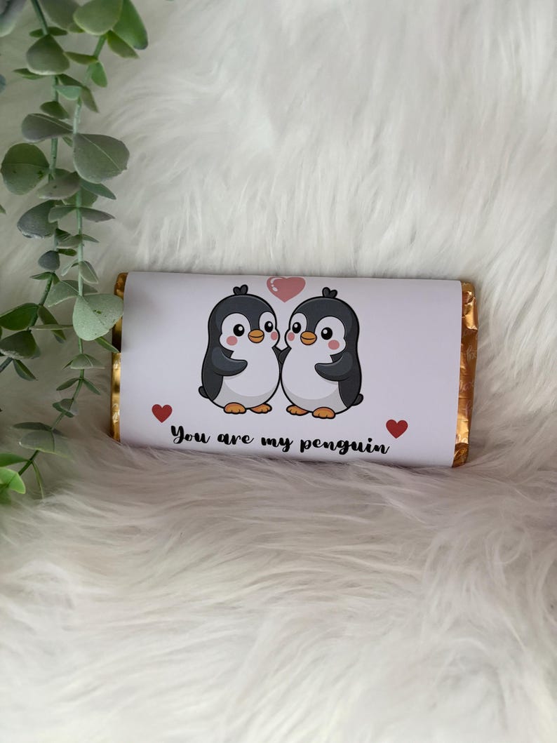 May include: A chocolate bar wrapped in white paper featuring two cartoon penguins with a pink heart above them. The text "You are my penguin" is printed below the penguins, with red heart accents.