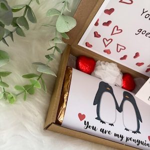 May include: A gift box with a white card featuring two penguin illustrations holding hands, with the text "You are my penguin". The box contains a chocolate bar, red foil-wrapped heart-shaped candies, and a white flower.
