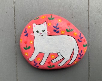 White cat on pink garden background painted rock