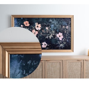 May include: A framed floral painting with a gold-colored frame. The artwork features pink flowers and green leaves against a dark background. The frame has a detailed, textured design. The painting is displayed above a wooden cabinet.