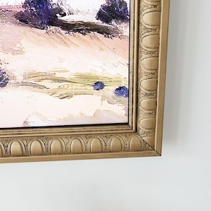 May include: A framed abstract landscape painting with a gold ornate frame. The painting features a light background with brushstrokes of purple, pink, and green.