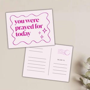 May include: Two light pink postcards. The top card has the text "you were prayed for today" in a wavy, magenta frame with star accents. The bottom card has lines for writing and a "DELIVER TO" section.