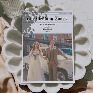 May include: A wedding announcement titled "The Wedding Times" featuring a photo of a couple. The announcement includes the names Mr. & Mrs. Robinson, the location London, and the date 15th March 2025. The announcement is on a white scalloped tray.