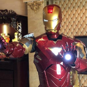 Pode incluir: Um traje de Iron Man vermelho e dourado com uma luz brilhante na palma da mão.