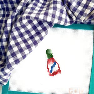 May include: A white canvas with a green, red, and blue cross-stitch design of a Christmas stocking. The canvas is framed with a teal border. The text "C-20" is visible in the bottom right corner.