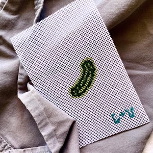 May include: A white canvas with a green and yellow pickle design and the text "L+U" in blue.