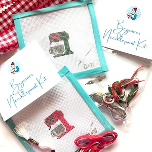 May include: Needlepoint kits for beginners, featuring a red and green stand mixer design. The kits include a needlepoint canvas, thread, scissors, and a needle. The kits are packaged with a red and white gingham ribbon.