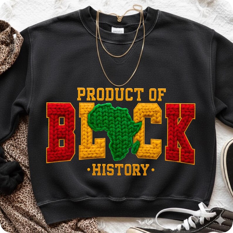 May include: Black sweatshirt with the text "PRODUCT OF BLACK HISTORY" in yellow, red, and green. The word "BLACK" features a green Africa map in the center. A gold necklace is draped on the sweatshirt.
