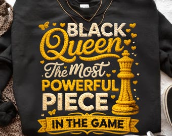 Puede incluir: Sudadera negra con el texto "BLACK Queen The Most Powerful Piece In The Game" en amarillo y blanco. El diseño incluye una pieza de reina de ajedrez amarilla y corazones y mariposas decorativas.
