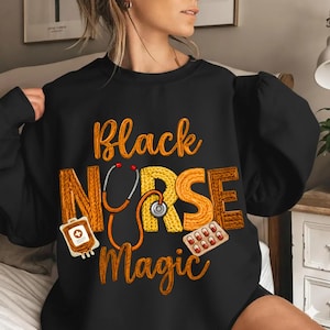 May include: Black sweatshirt with the words "Black Nurse Magic" in orange and brown lettering. The design includes a stethoscope, a bag of blood, and a blister pack of pills.