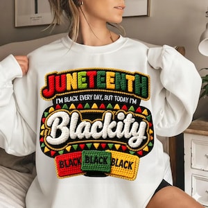Puede incluir: Sudadera blanca con un dise&ntilde;o gr&aacute;fico colorido. El dise&ntilde;o incluye la palabra "Juneteenth" en rojo, verde y amarillo, junto con la palabra "Blackity" en blanco. Debajo, tres parches rectangulares con la palabra "Black" en cada uno.