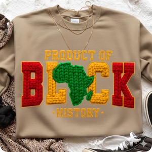 May include: Tan sweatshirt with the words "PRODUCT OF BLACK HISTORY" in yellow and red knit lettering. The letter "B" is red, the "LACK" is yellow, and the "K" is red. A green knit Africa map is in the center.