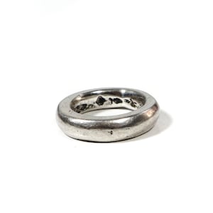 May include: A silver ring with a smooth, rounded surface. The ring is simple and minimalist in design.