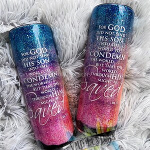 May include: Two colorful, glittery tumblers with a Christian quote about God sending his son into the world to save it. The quote is "For God did not send his son into the world to condemn the world, but that the world through him might be saved." The tumblers have a gradient of blue, pink, and orange.