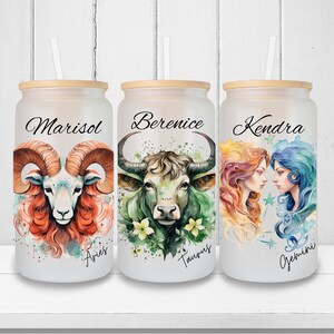 Puede incluir: Tres vasos de vidrio esmerilado con tapas y pajitas de bambú. Cada vaso presenta una ilustración de acuarela de un signo del zodíaco: Aries, Tauro y Géminis. Los vasos están personalizados con los nombres Marisol, Berenice y Kendra.