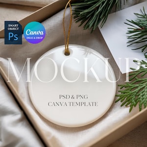 May include: A white ceramic ornament with a gold string, inside a box with greenery. The ornament has the word "MOCKUP" in large letters and the text "PSD & PNG CANVA TEMPLATE". A blue and teal Canva logo is in the upper left.