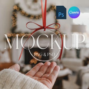 May include: A clear glass ornament with a red ribbon and bow hanging from it. The ornament has the text "MOCKUP PNG & PSD" printed on it. The ornament is in front of a blurred background of a Christmas tree and fireplace.