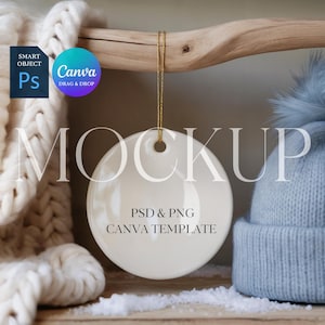 May include: A white, round ceramic ornament with a gold string, hanging from a wooden branch. The ornament has the text "PSD & PNG CANVA TEMPLATE" on it. A blue knit hat with a pom-pom is in the background.