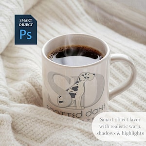 K&ouml;nnte beinhalten: Eine wei&szlig;e Keramiktasse mit schwarzem Henkel, gef&uuml;llt mit Kaffee und aufsteigendem Dampf. Die Tasse hat ein Motiv eines gefleckten Hundes mit dem Text "Spotted Dane" auf der Vorderseite.