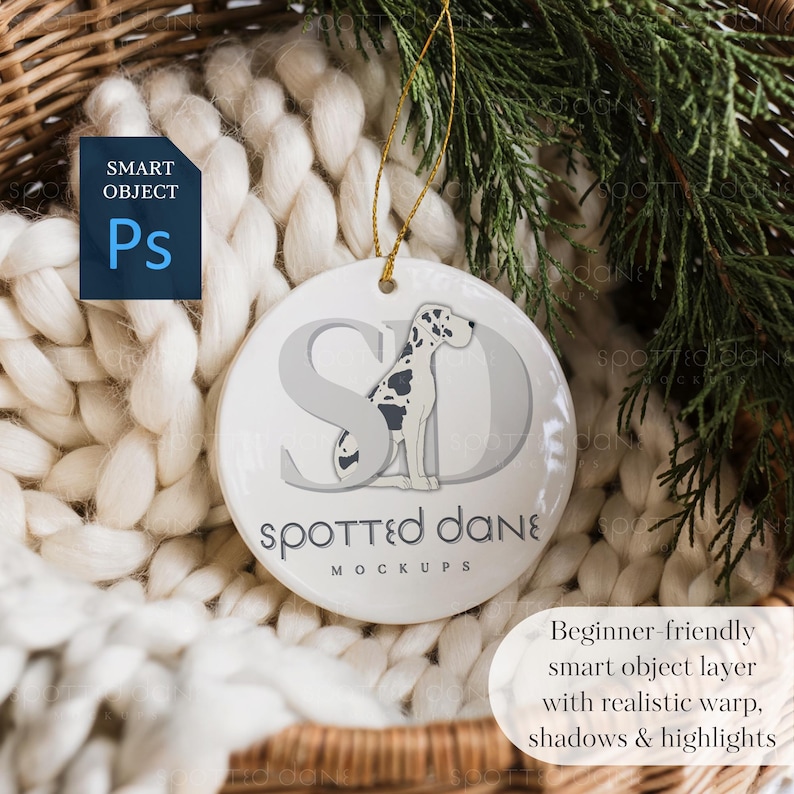 May include: A white ceramic ornament with a Dalmatian dog design and the text "Spotted Dane Mockups." The ornament hangs from a gold string. The background includes a white knitted blanket and greenery.