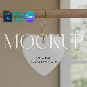Puede incluir: Un adorno blanco en forma de corazón con una cuerda dorada, colgado de una barra de madera. La palabra "MOCKUP" se muestra encima del corazón. Debajo del corazón, el texto dice "PSD & PNG CANVA TEMPLATE".