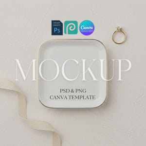 Pode incluir: Um prato quadrado de cerâmica branca para anéis com borda dourada, acompanhado por um anel dourado com uma pedra transparente. A imagem apresenta sobreposições de texto, incluindo MOCKUP, PSD & PNG, CANVA TEMPLATE e ícones Smart Object, Ps e Canva.
