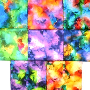 May include: Nine square fabric pieces with abstract watercolor designs. The squares feature a variety of colors, including blue, green, purple, orange, and yellow. The designs have a marbled or cloud-like appearance, with gold accents.