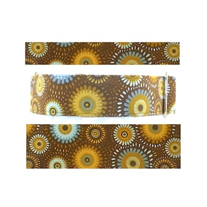 May include: A brown dog collar with a repeating pattern of yellow, blue, and white circular designs. The collar has a metal buckle and is shown in three sections against a white background.