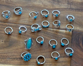 May include: A set of 20 silver rings with turquoise stones. The rings feature various designs, including simple bands, floral motifs, and geometric shapes.
