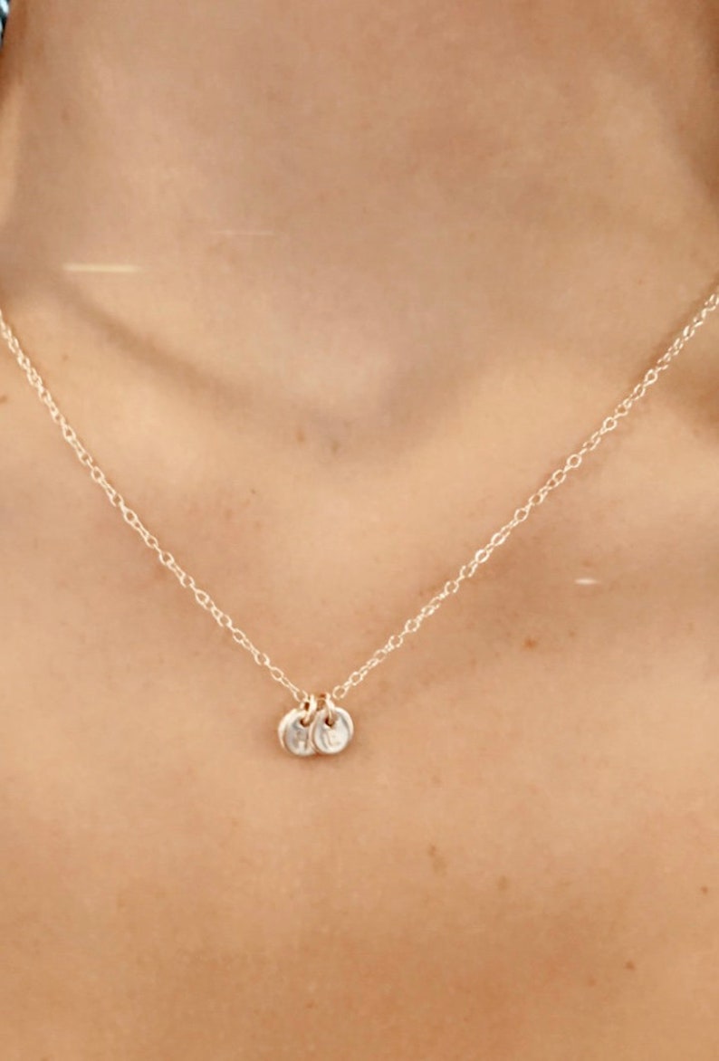May include: A silver chain necklace with two small silver discs as pendants.