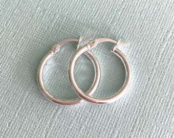 May include: A pair of silver hoop earrings. The earrings are simple and classic, with a smooth, polished finish.