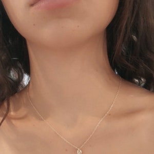 May include: A delicate gold chain necklace with a small, round pendant. The pendant appears to be a simple, minimalist design.