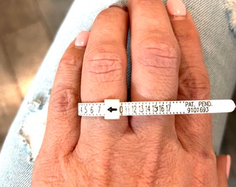 May include: A white plastic ring sizer with black markings from size 4 to 17. The text "PAT. PEND. 9101693" is printed on the sizer.