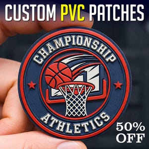 Op de afbeelding: Een ronde, op maat gemaakte PVC-patch met een basketbalthema. De patch toont een basketbal, een basket en de woorden "CHAMPIONSHIP ATHLETICS". Het ontwerp is in rood, wit en blauw, met de tekst "CUSTOM PVC PATCHES" bovenaan.