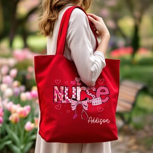May include: A red tote bag with the word "NURSE" in a pink and white design, with hearts and a stethoscope graphic. The name "Addison" is printed below the graphic. The bag has red handles.