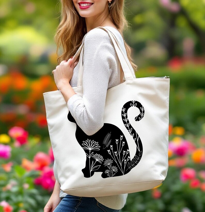 K&ouml;nnte beinhalten: Eine wei&szlig;e Einkaufstasche mit einer schwarzen Silhouette einer Katze mit floralen Details am Schwanz. Die Katze sitzt mit ihrem Schwanz um ihren K&ouml;rper gewickelt.