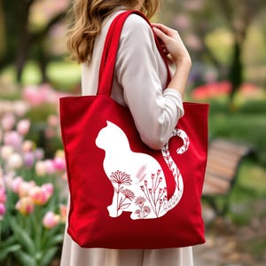 K&ouml;nnte beinhalten: Rote Stofftasche mit einer wei&szlig;en Silhouette einer Katze mit floralen Designs innerhalb der Silhouette.