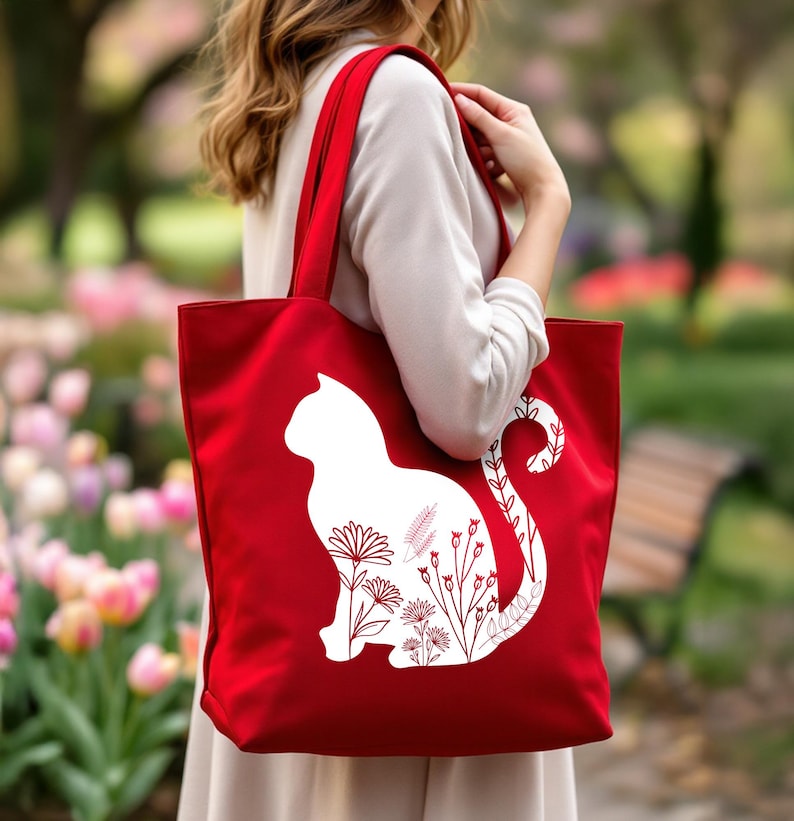 K&ouml;nnte beinhalten: Rote Stofftasche mit einer wei&szlig;en Silhouette einer Katze mit floralen Designs innerhalb der Silhouette.