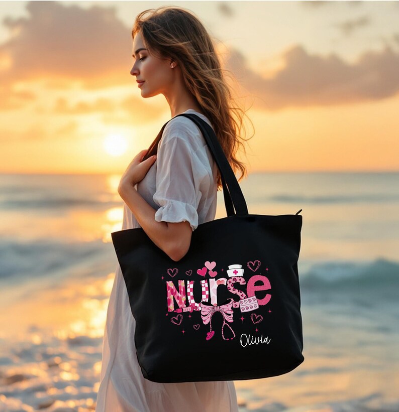 May include: Black tote bag with the word "Nurse" in pink and white checkered letters, surrounded by pink hearts and a stethoscope. The name "Olivia" is printed below the word "Nurse".