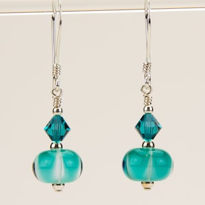 May include: Teal and white glass bead earrings with a teal crystal accent and silver wire.
