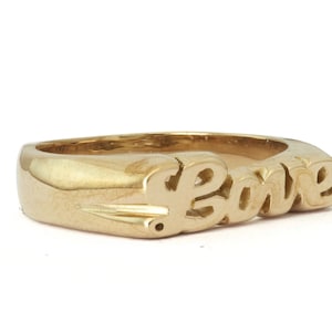 May include: A gold ring with the word "Love" spelled out in a stylized font.