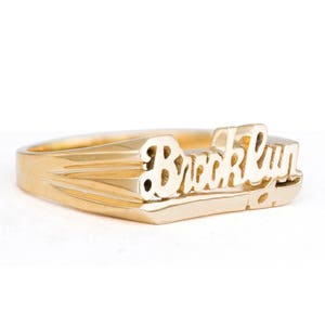 May include: A gold ring with the word "Brooklyn" engraved on it.