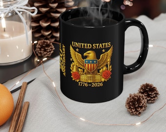 Könnte beinhalten: Schwarze Keramik-Tasse mit einem goldenen Emblem der Vereinigten Staaten, das einen Adler, Sterne und die Aufschrift "UNITED STATES" und "1776-2026" zeigt. Die Tasse hat einen gebogenen Henkel und enthält eine dunkle Flüssigkeit, möglicherweise Kaffee oder Tee.