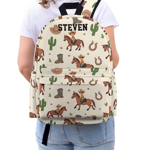 Könnte beinhalten: Ein beigefarbener Rucksack mit Cowboy-Motiv. Der Rucksack hat ein sich wiederholendes Muster von Cowboys auf Pferden, Kakteen, Cowboy-Stiefeln und Hufeisen. Der Name "STEVEN" ist oben auf dem Rucksack aufgedruckt.