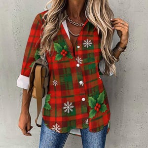 May include: Red and green plaid button-down shirt with white cuffs. The shirt features holly and snowflake designs. The shirt is a festive holiday-themed top.