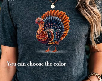 Puede incluir: Una camiseta gris jaspeado oscuro con un gráfico de pavo vibrante y multicolor con patrones intrincados en tonos naranja, azul y rojo. El texto GinnyGiFinds, Enjoy your Life with design y You can choose the color está impreso.