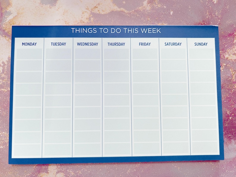 A weekly planner notepad with a dark blue border. The days of the week are listed across the top: Monday, Tuesday, Wednesday, Thursday, Friday, Saturday, Sunday.  Each day has multiple blank lines for writing tasks or appointments. The title at the top reads: 'Things To Do This Week'.