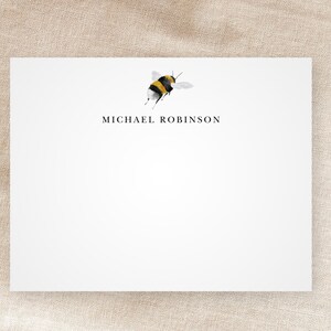 May include: White stationery card with a black and yellow bumblebee illustration and the text "MICHAEL ROBINSON" printed in black.